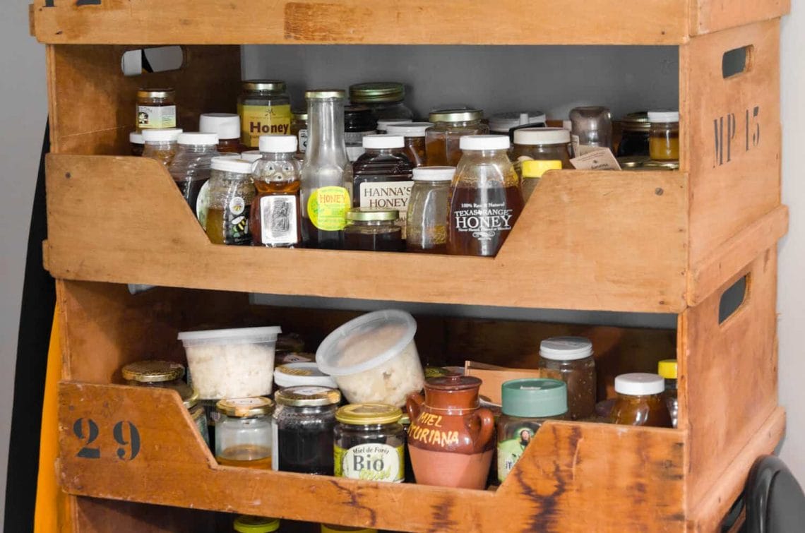 Various bottles of honey on wooden shelves 