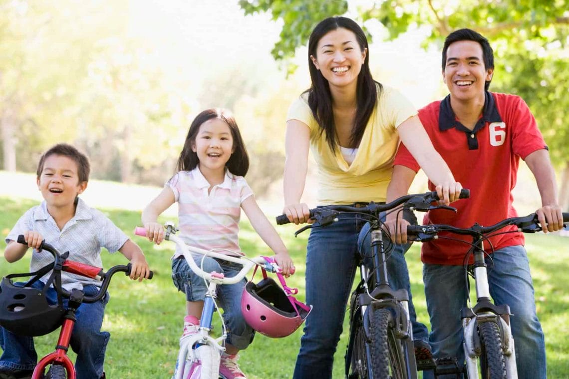 A family outdoors cycling together happily 