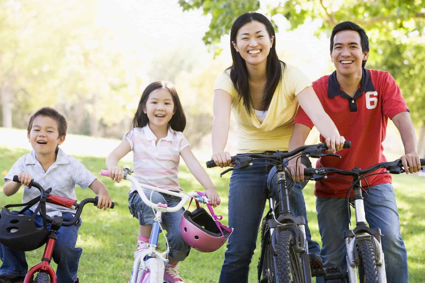 A family outdoors cycling together happily 