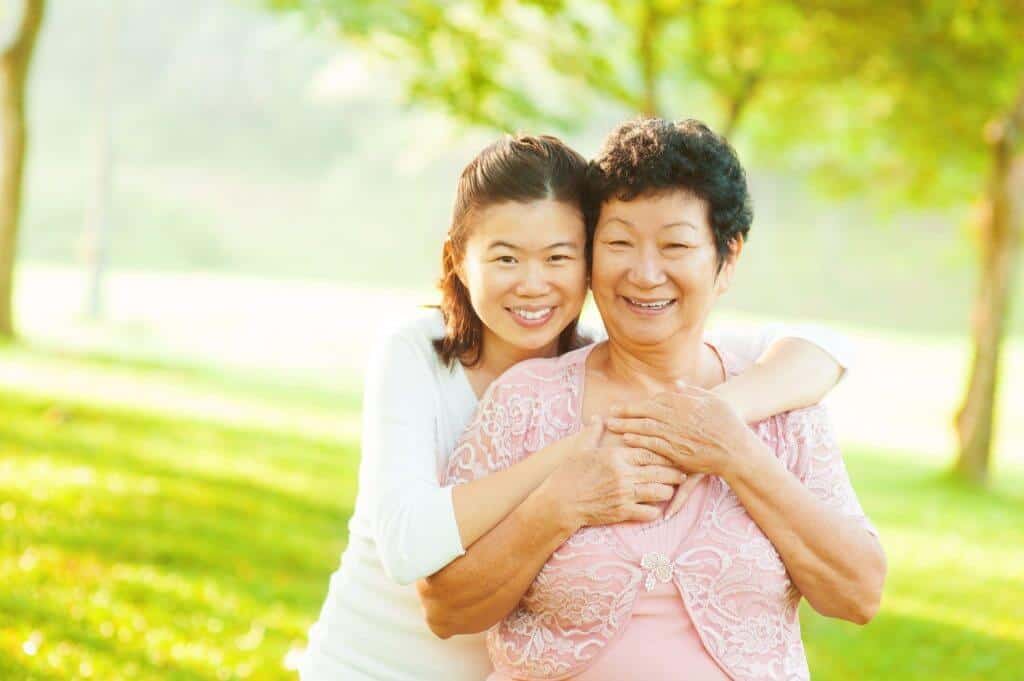 Younger Asian lady hugging an older lady and smiling