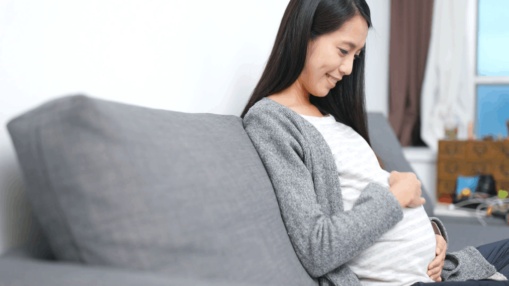 Pregnant woman smiling while caressing her baby bump