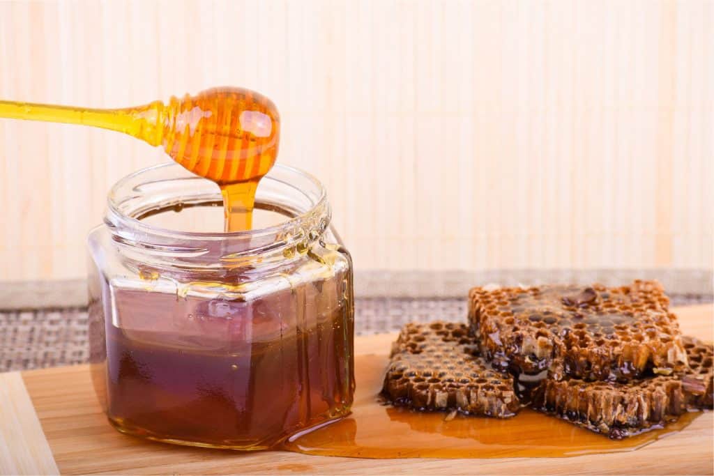 Honey in a jar and a pile of honeycomb on the right