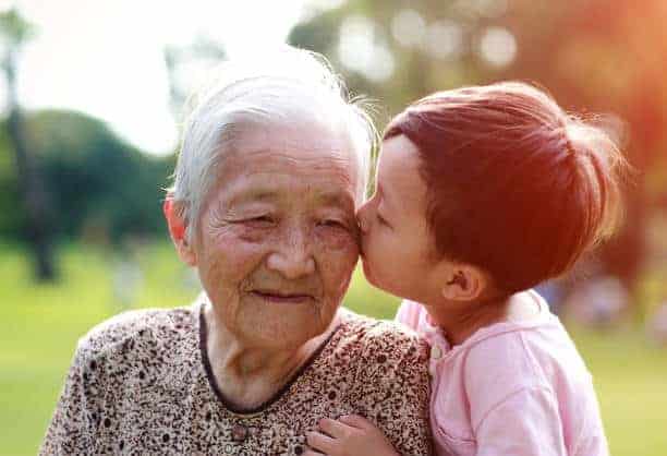 Young asian boy kissing an elderly grandmother on the cheek