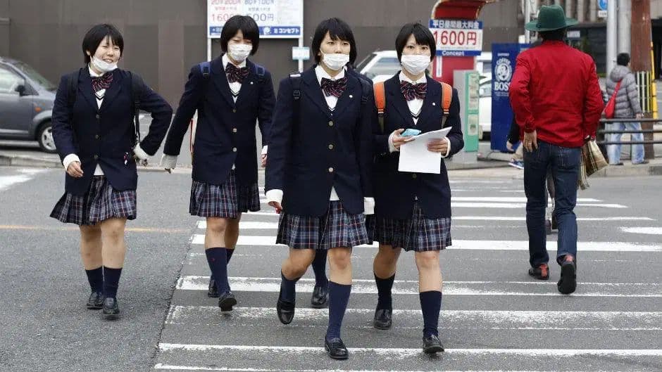 Group of Japanese female students wearing masks crossing the street